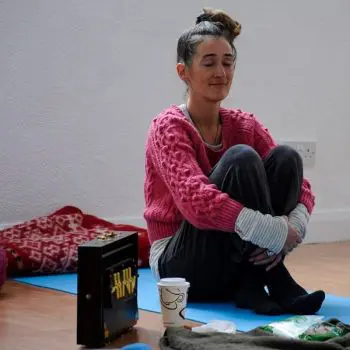 A slim girl sitting on a blue yoga mat