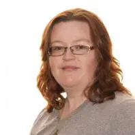 Fat & thick-haired woman wearing a jersey and glasses looking at Nidra's Massage Center