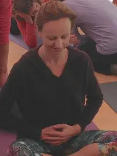 A Woman teaching a yoga class, with students following along