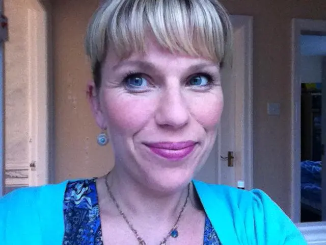 The brown-haired, smiley woman takes a selfy in Relax Massage Center in front of the door