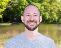 A smiling man his background is a Lake of water