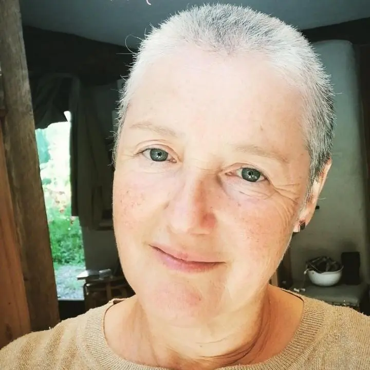 The bald old woman standing in her kitchen, her backside is open door | The House of Yoga