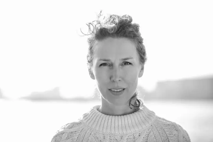 In a black, and white photo, A pretty girl wearing a jersey to start her yoga journey