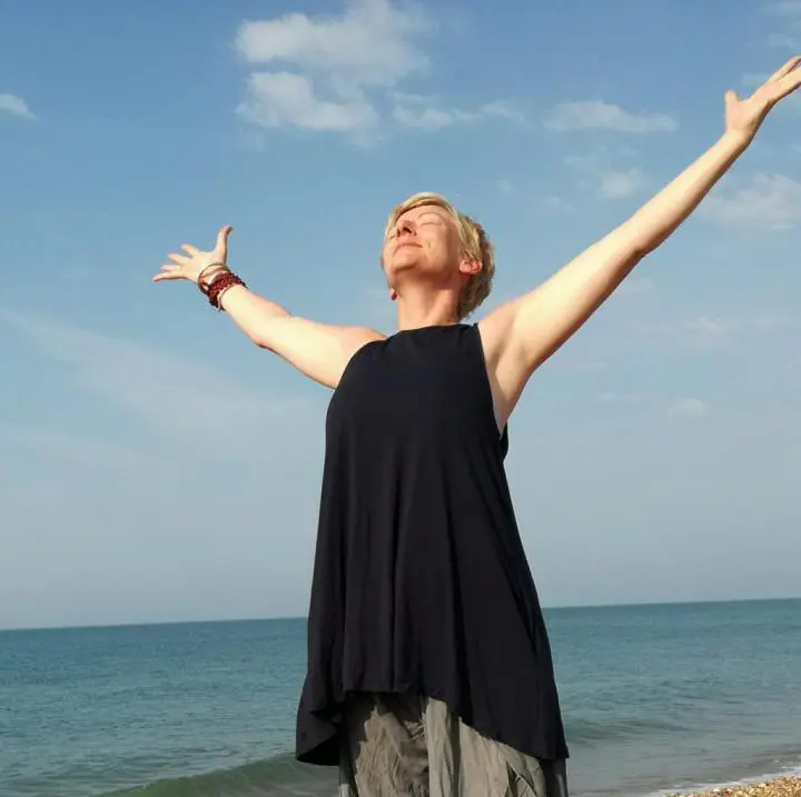 A Woman performing a backbend pose in yogism, with their arms extended and their face turned upward