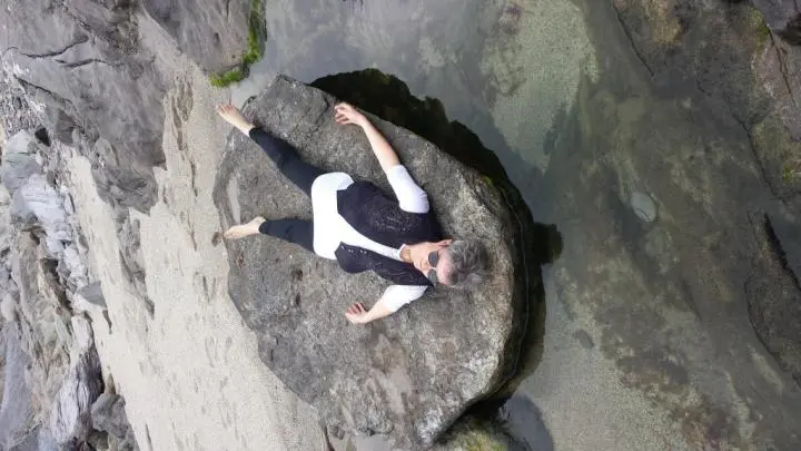 She is lying on a stone with her extended legs & arms overhead, Mood-Boosting Activities During Yoga