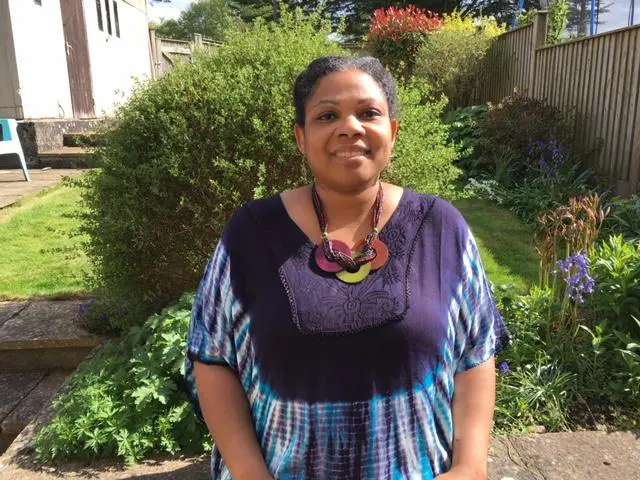 A 45-year-old woman standing on her lawn, taking yoga in my fresh air barn with beautiful natural background