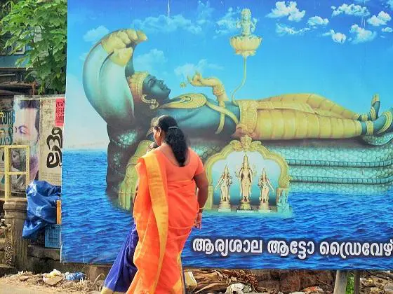 A female Yoga Nidra instructor standing from the front of the Statue of Hindu deity Sri Anantha Padmanabha Swamy temple