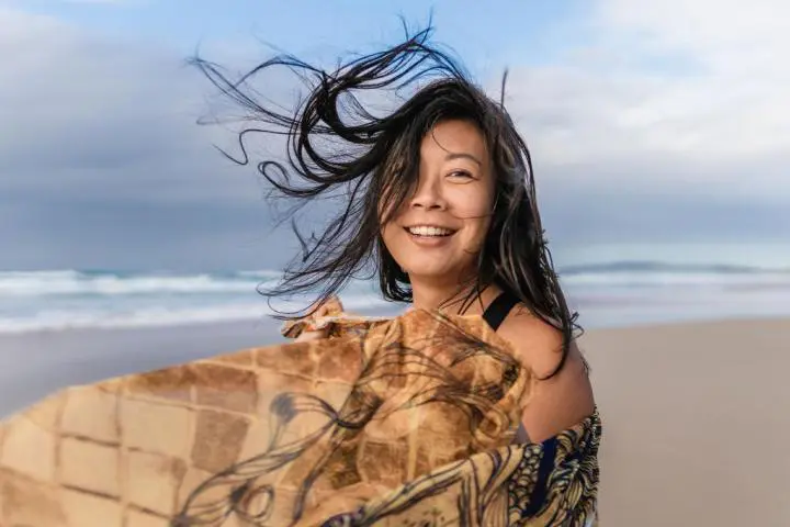 A smiling woman at the beach of the ocean