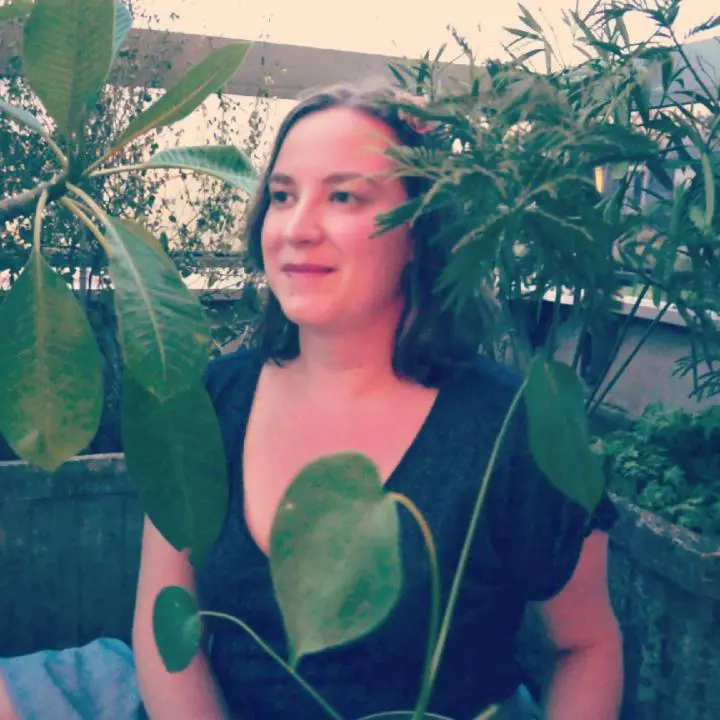 A woman standing on our home balcony surrounded by trees leaves
