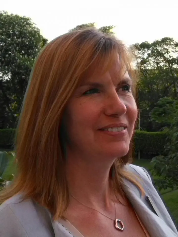 A lady standing on her lawn who her brown long hair & she seeing a Male Yoga instructor