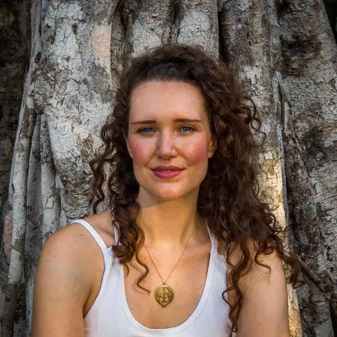 An aesthetic girl leans to a tree who has curly hair and feels better after doing massage/yoga