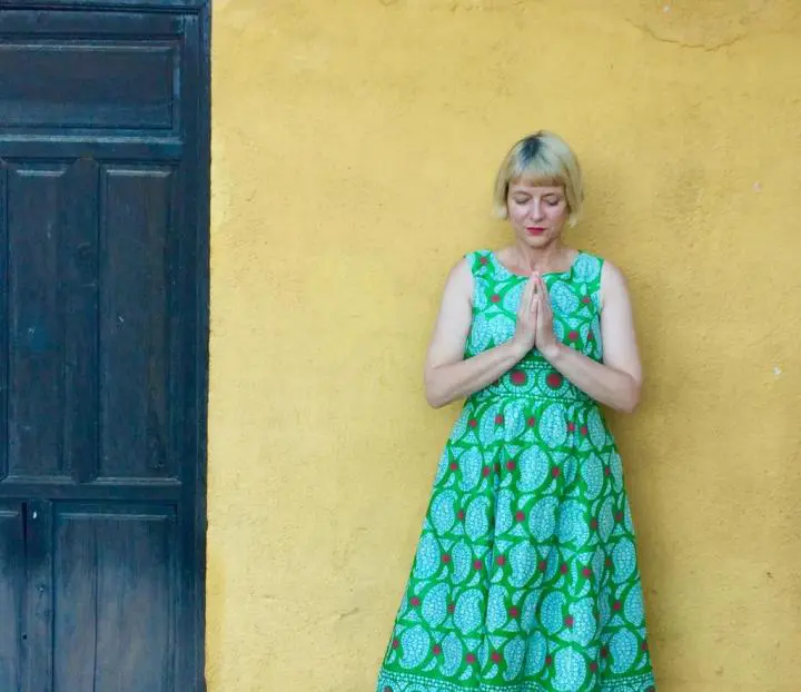 A slim woman leans with wall and we see her left side is the massage room door