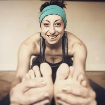 A Woman practicing yoga, with their feet, twisted and their arms extended