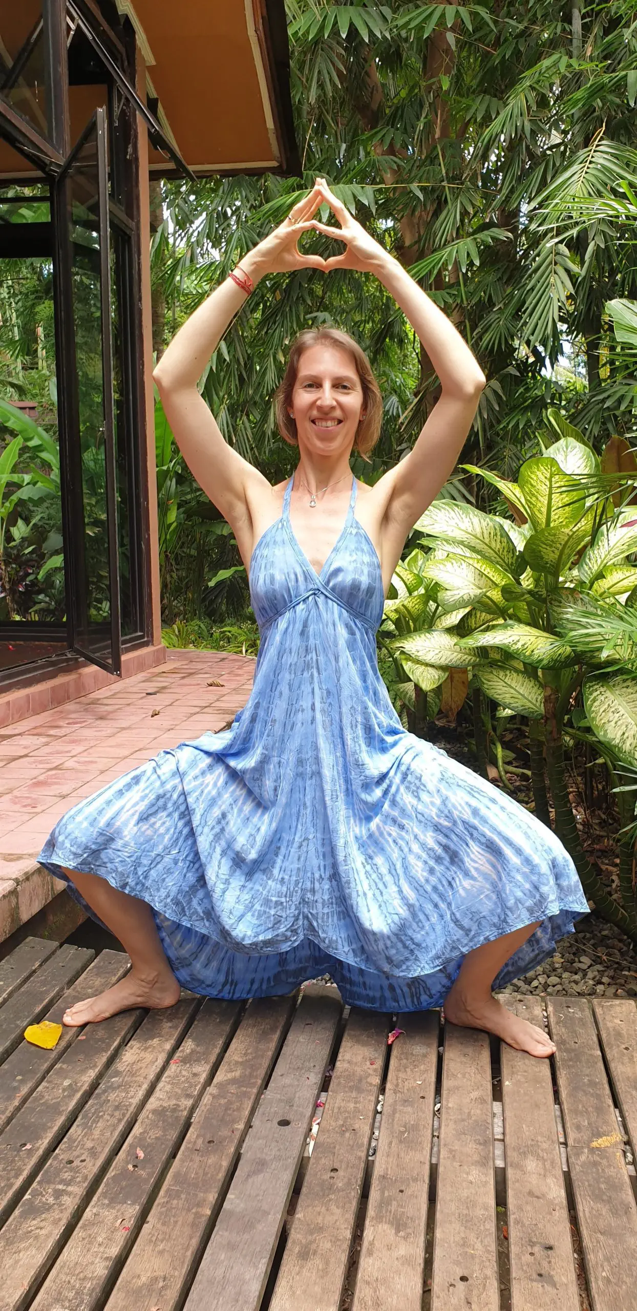 A lady performing a standing pose in yoga, with their legs & arms extended overhead