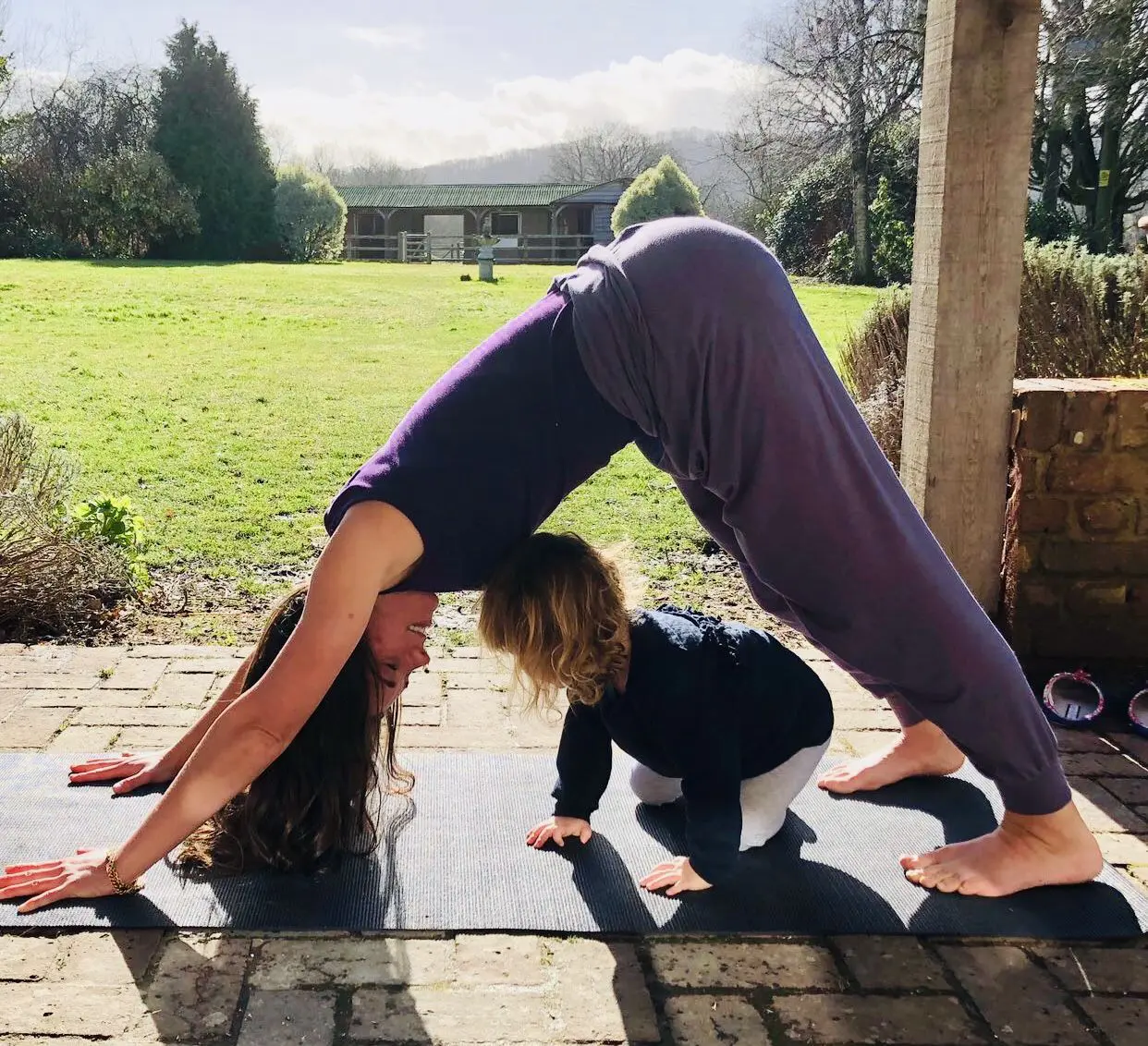 A young girl performing the Forward bends Yoga pose on her behind a little girl