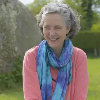 A 40+-year-old woman smiling in the grassy Endure of yoga Nidra house