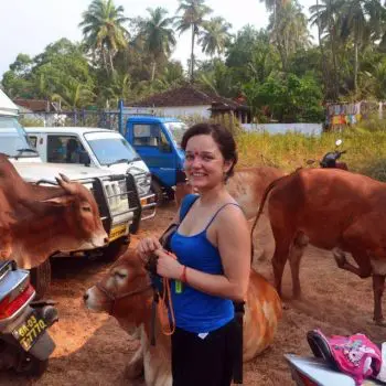 An Indian woman standing in Cow Mata hostel by many vehicles and his side date fruit