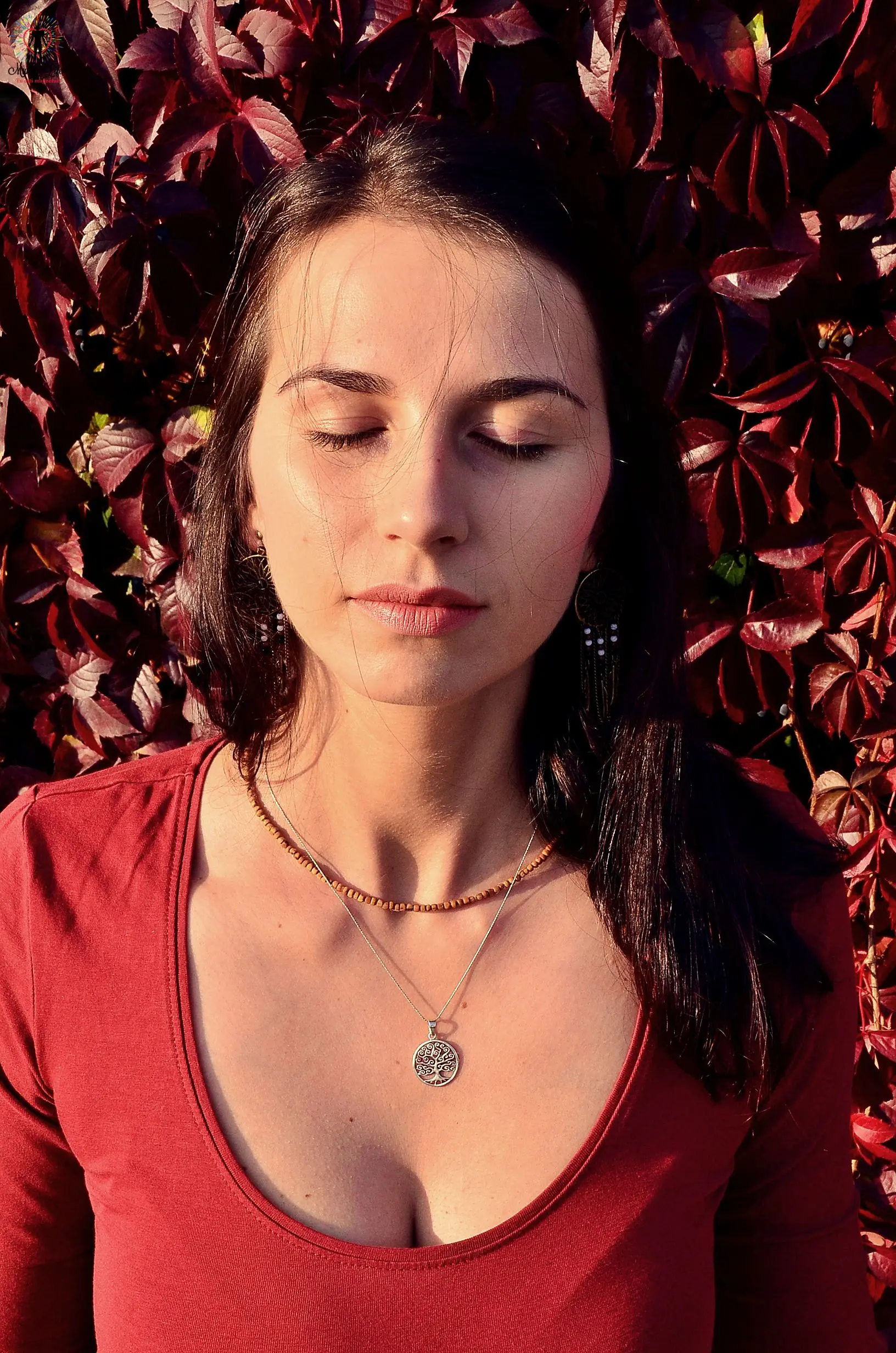 An aesthetic young girl lying on the leaves & wearing a necklace is feeling better after doing a massage
