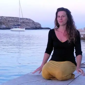 On the lake beach, a pretty girl sitting in the style yoga pose