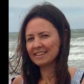 A young woman standing on the beach of the ocean, her long hair blowing in the wind