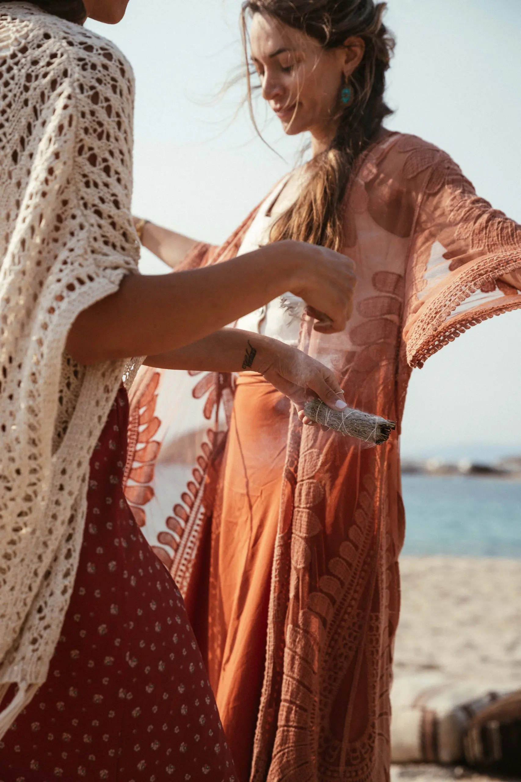 Two young girls standing on the beach of the ocean from those one girl holding chiropractic rollers