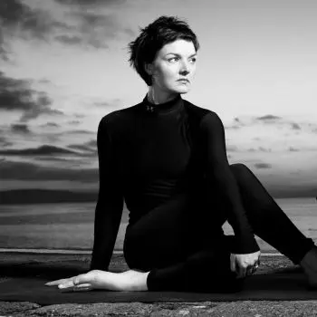 A young lady sitting in a meditative pose, surrounded by a textured background