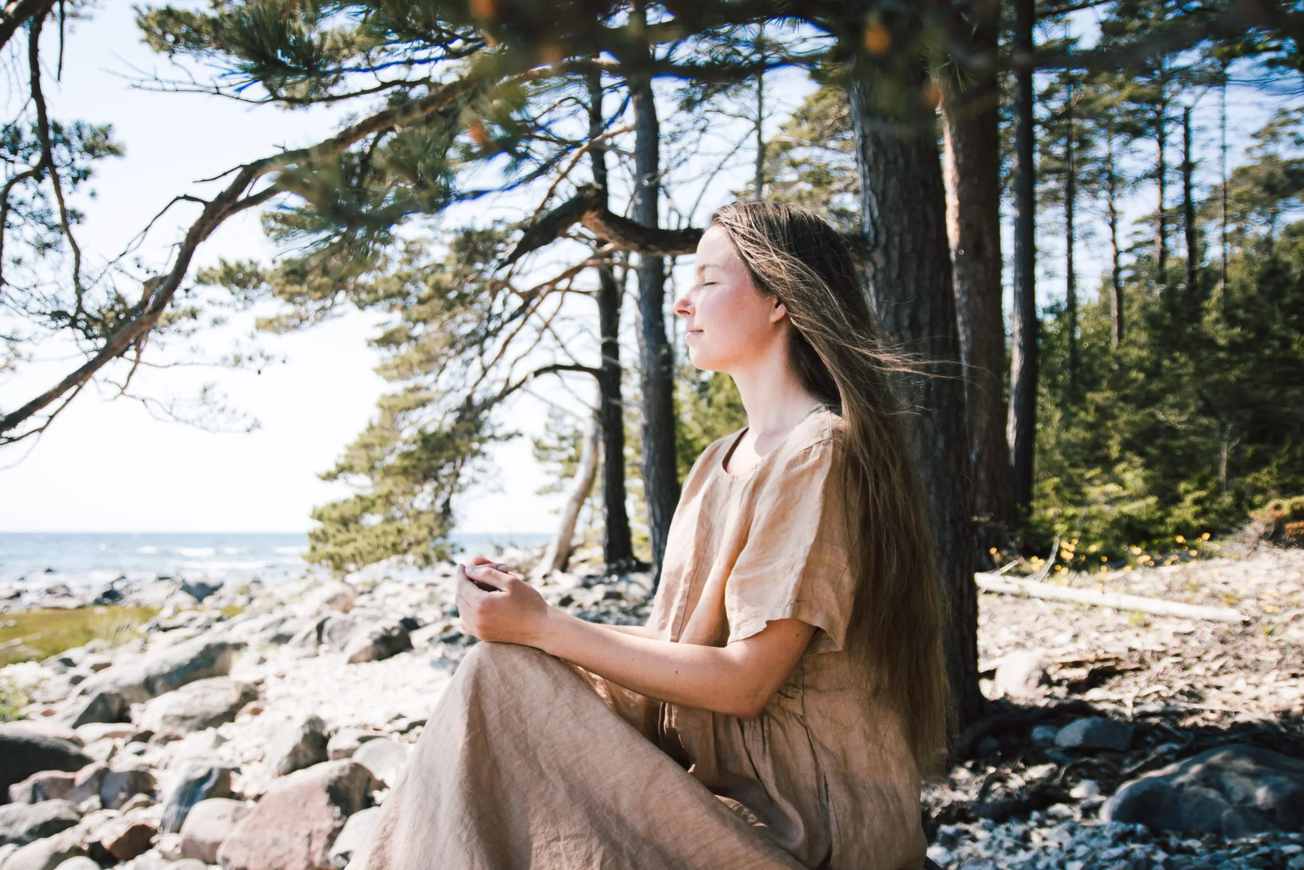 Such a lovely girl seated in yoga pose on a stone down on the tree