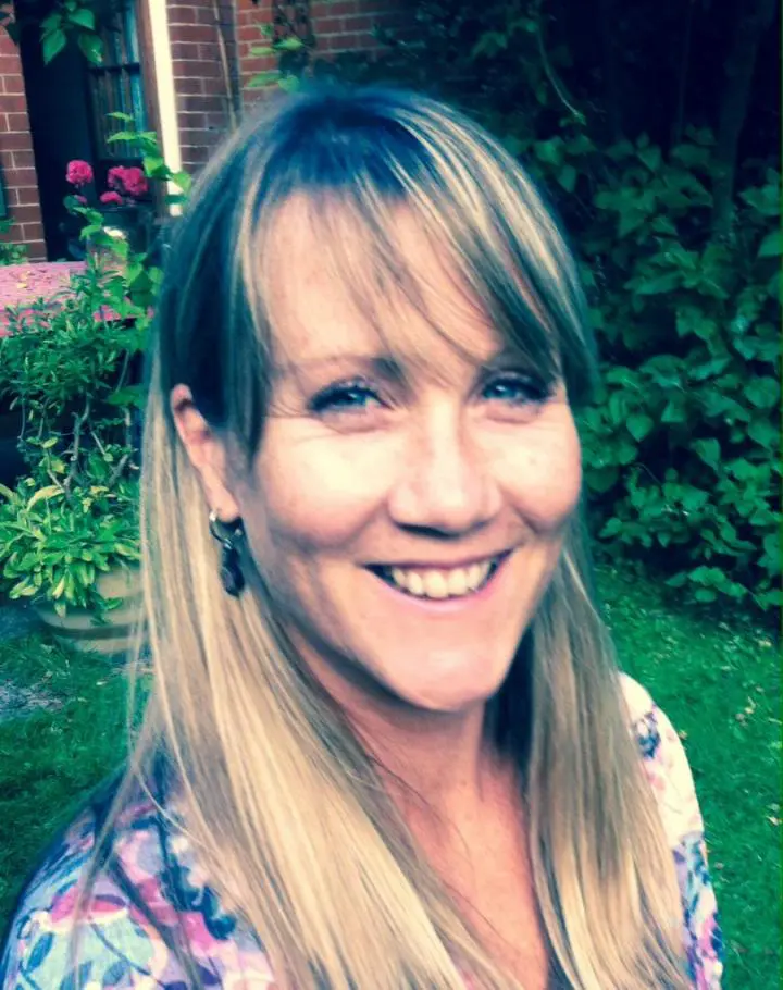 smiling and brown-haired White woman is standing on her lawn | Family Acroyoga class