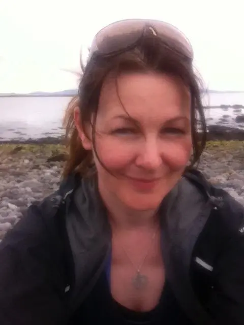 A smiling woman at head glasses on the beach of the river