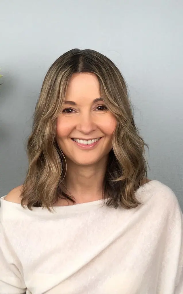 A Pretty young woman who has black & white hair, wearing a white chiropractic dress
