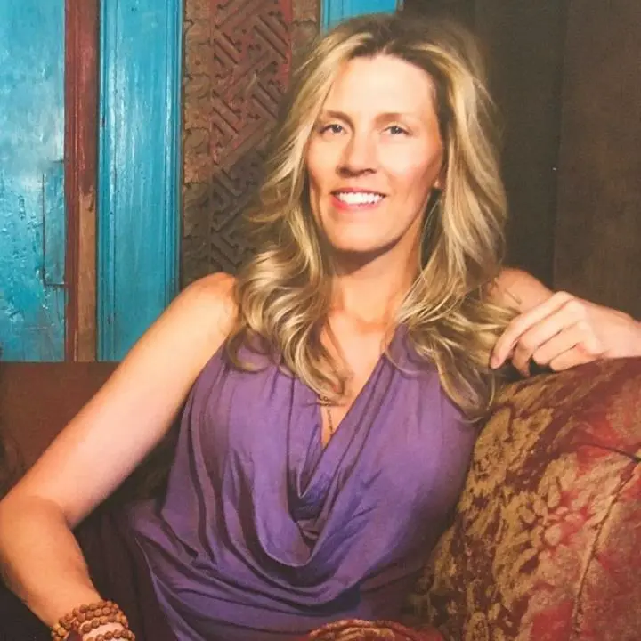 A brown-haired adult lady sitting on a sofa as a Special Yoga instructor