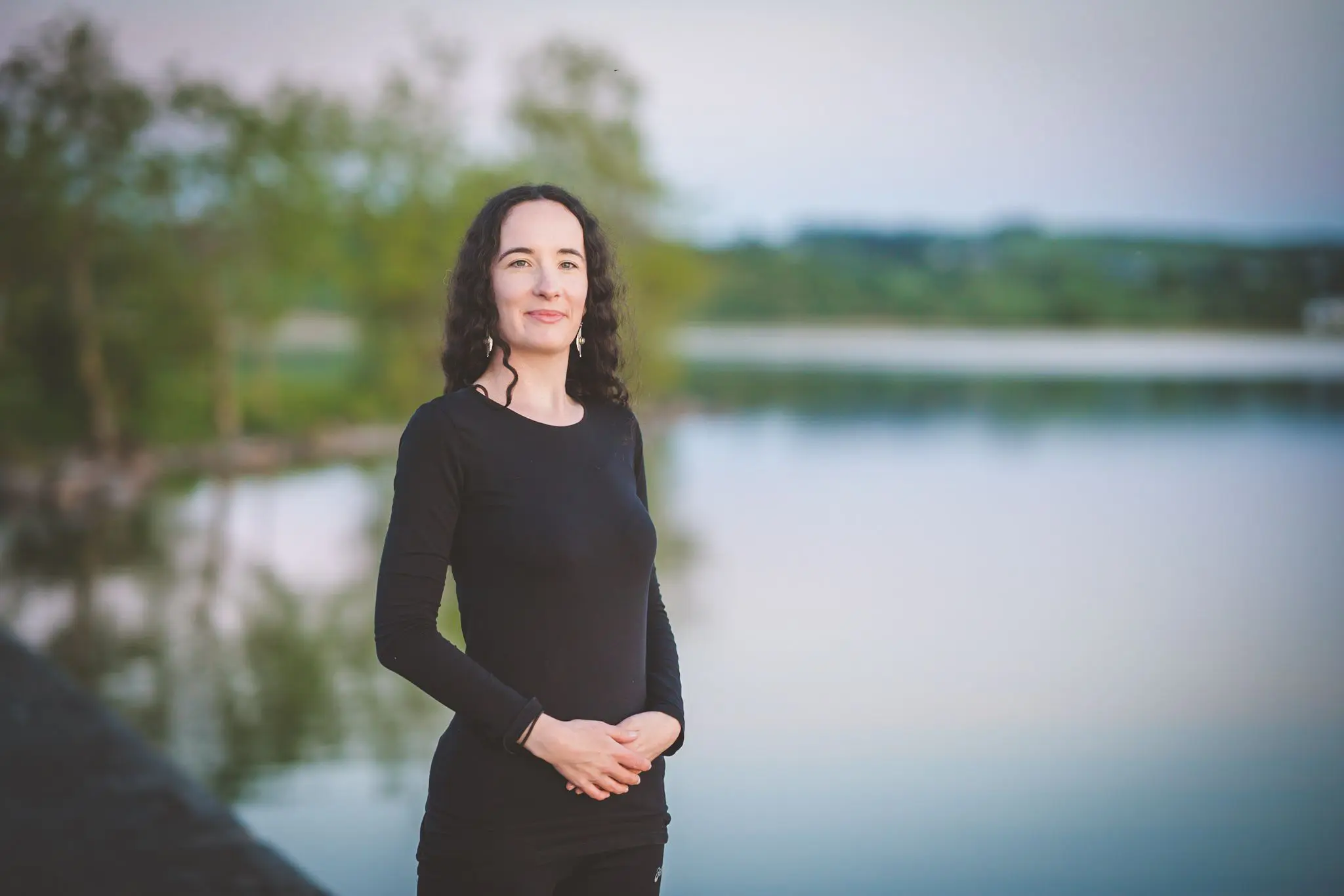 A Woman Standing in a yoga pose to teaching a Yoni Nidra class at the seaside of the river