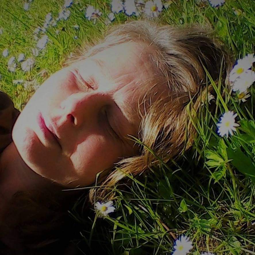 Brown-haired pretty lady lying on a grassy surface feeling better after doing Practice Of Pratyahara, surrounded by white followers