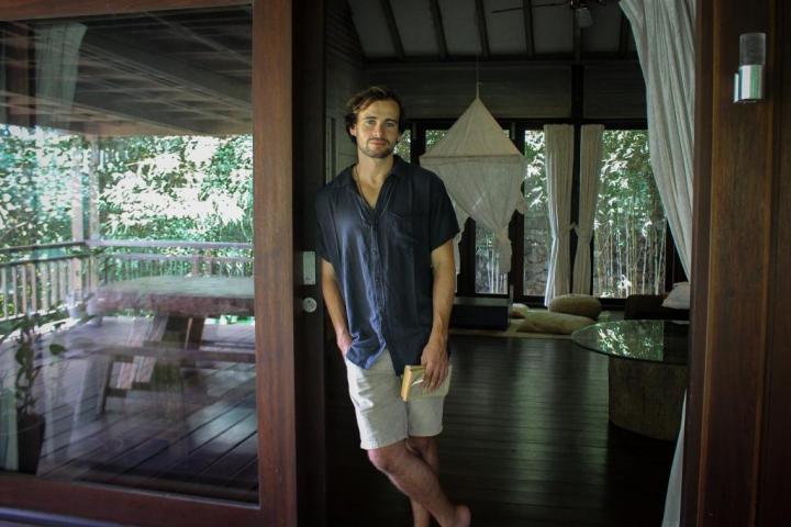 An adult Yoni Nidra teacher standing in the massage room, surrounded by a textured background