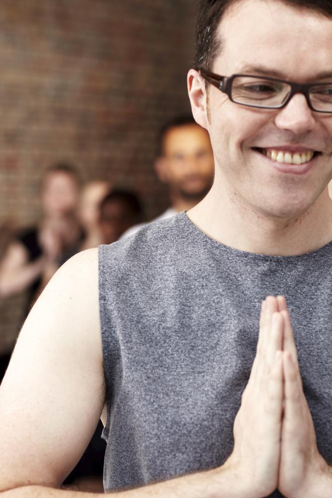 A glasses-man yoga instructor standing in Namaste pose