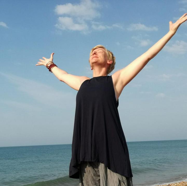 A Woman performing a backbend pose in yogism, with their arms extended and their face turned upward