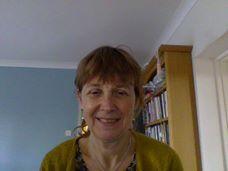Little haired old woman standing in Yoga Nidra's room and her backside is a books Closet