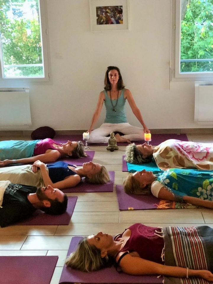 A Women teaching a yoga class, with students following along