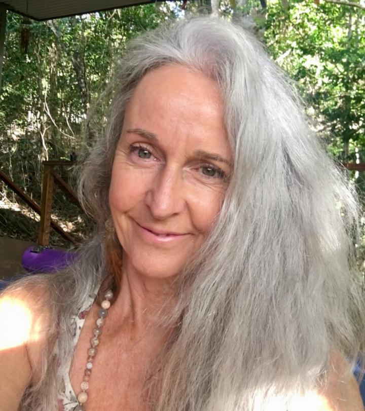 A white-haired old woman standing down the shade of a tree | Mother Nurture Yoga