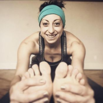A Woman practicing yoga, with their feet, twisted and their arms extended