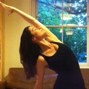 Such a pretty young girl making a yoga pose, with their extended arms in front of in bedroom window