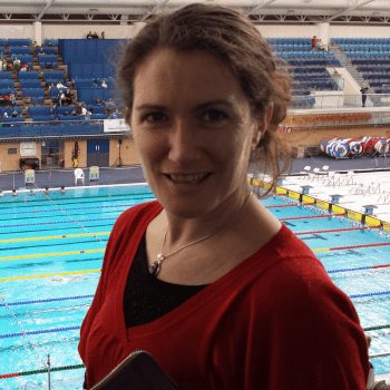 She is wearing a black bra and a red dress standing in the swimming stadium