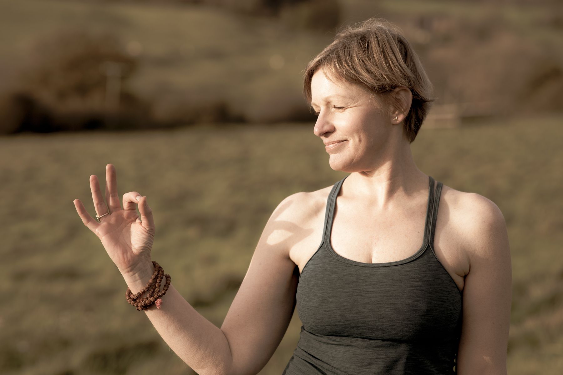 She is making a victory symbol with her hand and standing in the field to yoga in my fresh-air barn