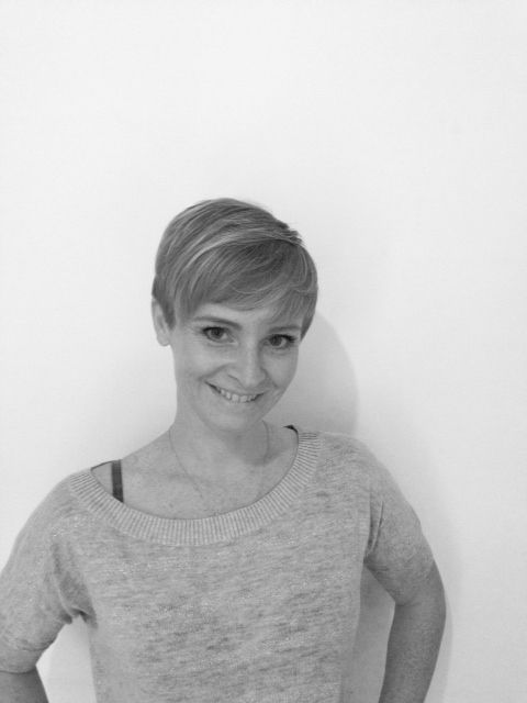 In a black, and white photo, a little-haired adult lady wearing a Yoga Therapist jersey