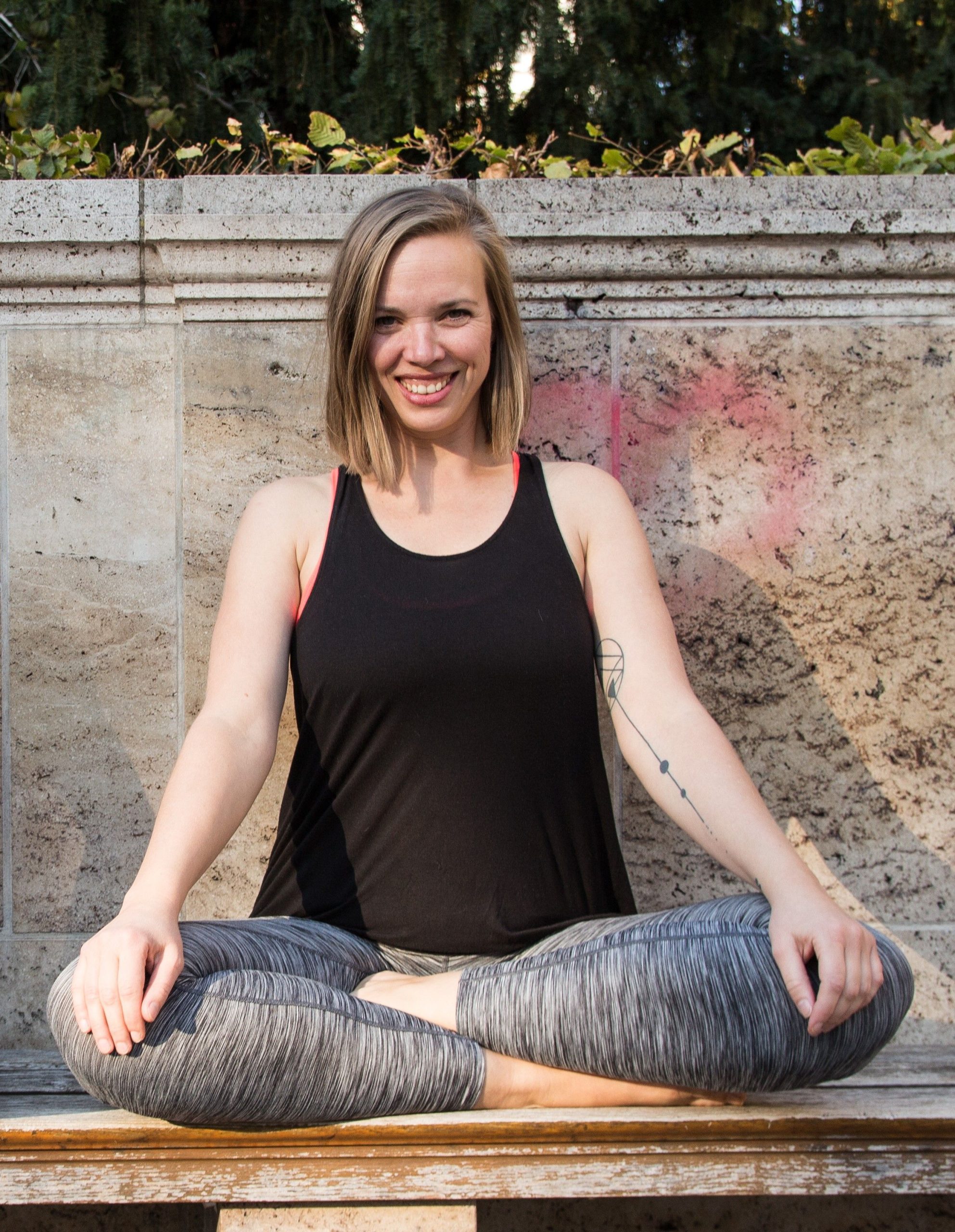 Our adult teacher sitting in yoga pose on the bench with her extended arms overhead