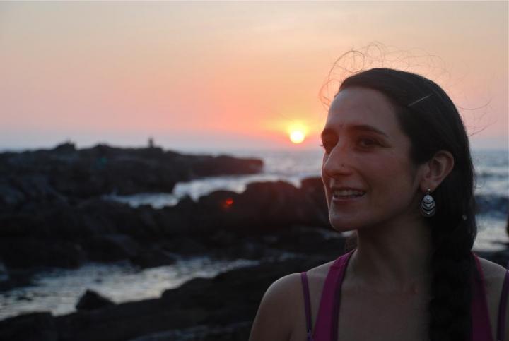 A young girl standing on the ocean with a beautiful view of the sunset