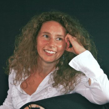 Curly & scattered-haired black woman seated in yoga pose on a sofa