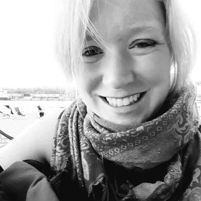 Such a beautiful girl who smiles teaching a yoga class, with students following along