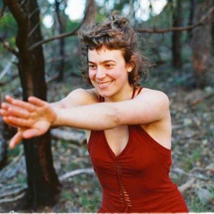 A young adult yoga instructor wearing a red sexy yoga dress with extended arms with her flips hands